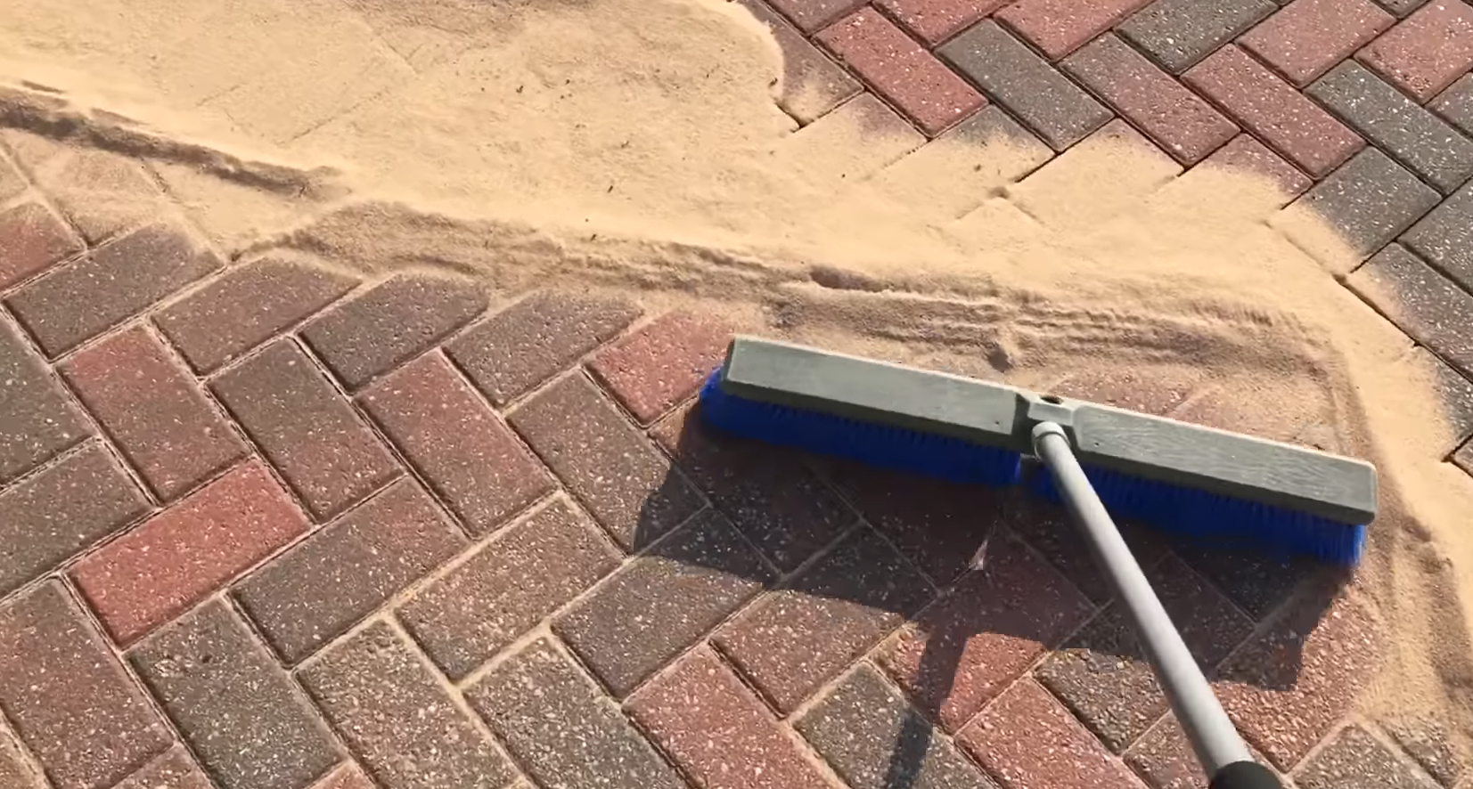 Photo of brushing sand into the gaps of block paving